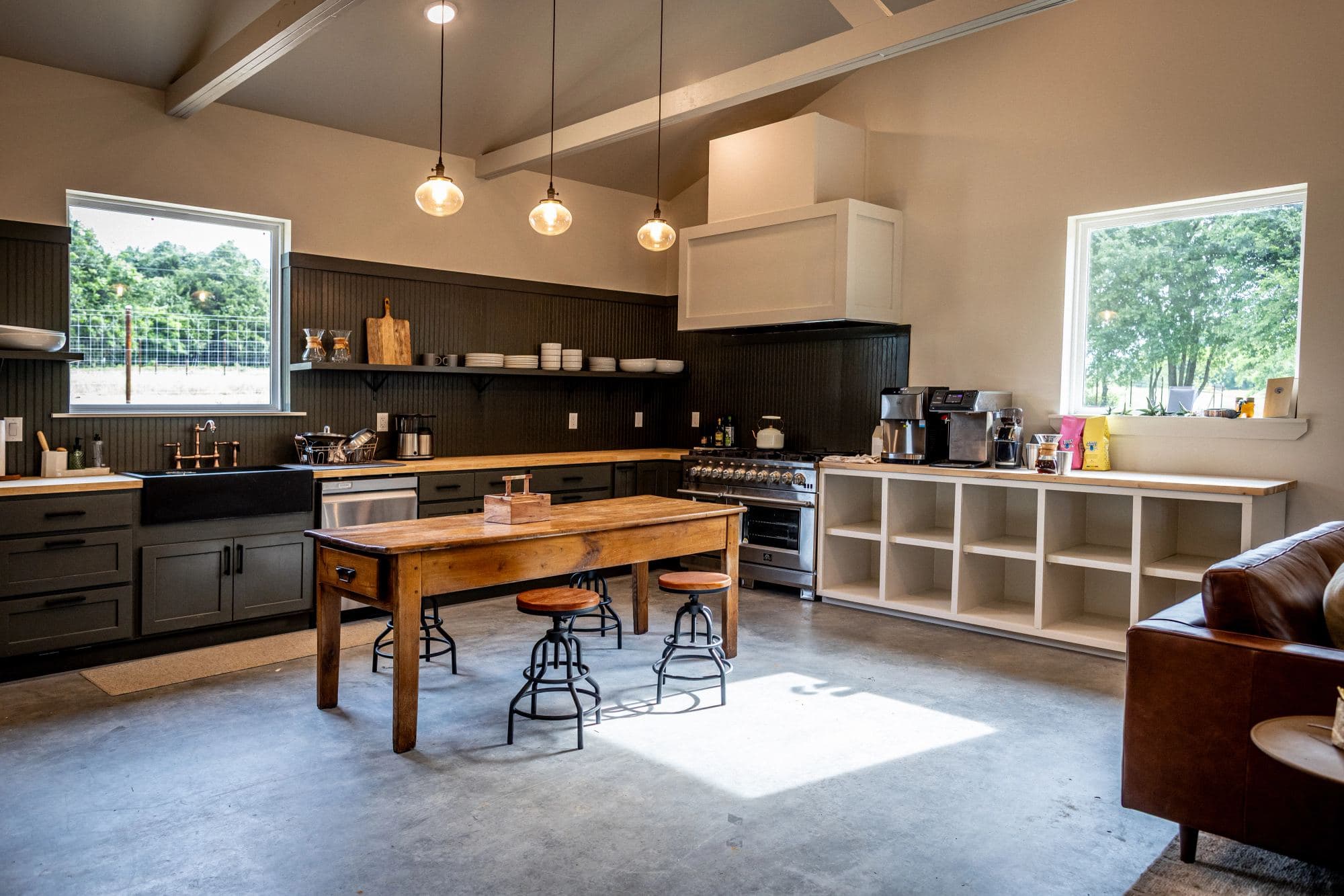 The Commons kitchen: long farm table, range, and open shelving